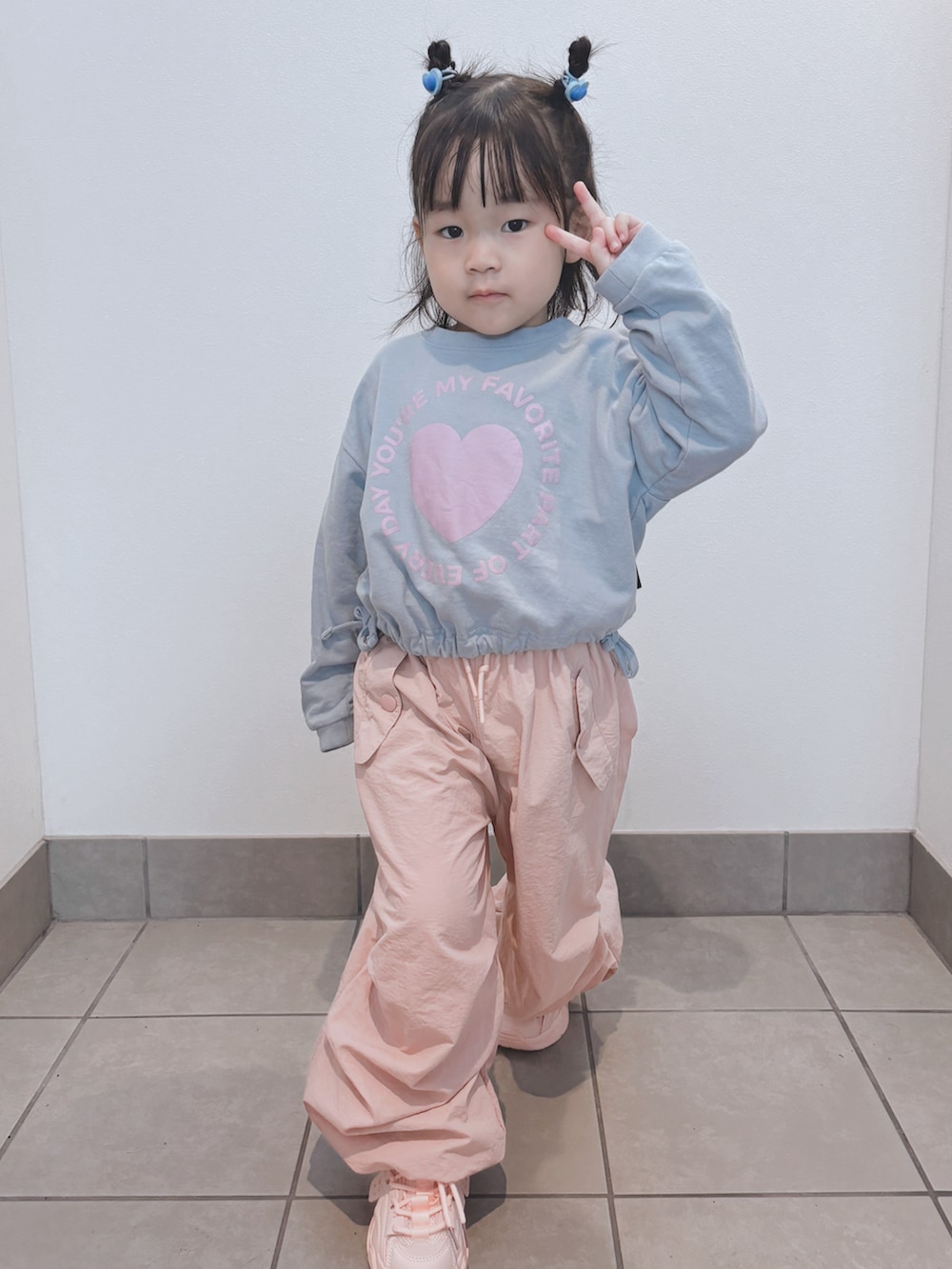 ブルー系のトップス、ピンク系のパンツ、ピンク系のスニーカーを着用したキッズの秋コーディネートの2枚目の写真