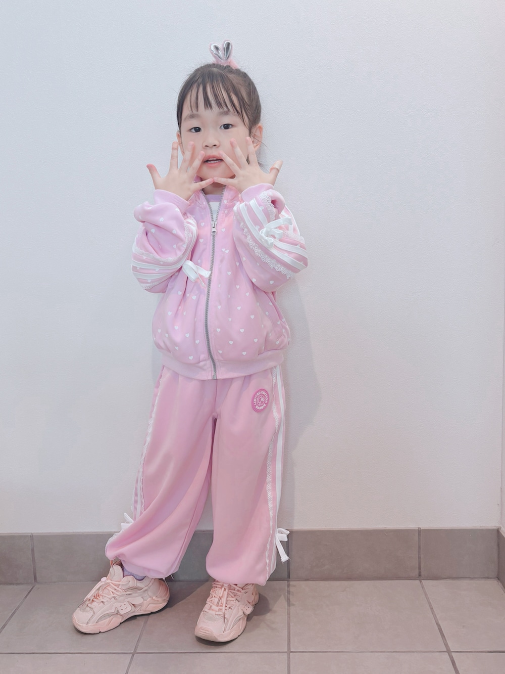 ピンク系のセットアップ、ピンク系のパンツ、ピンク系のスニーカーを着用したキッズの秋コーディネートの3枚目の写真