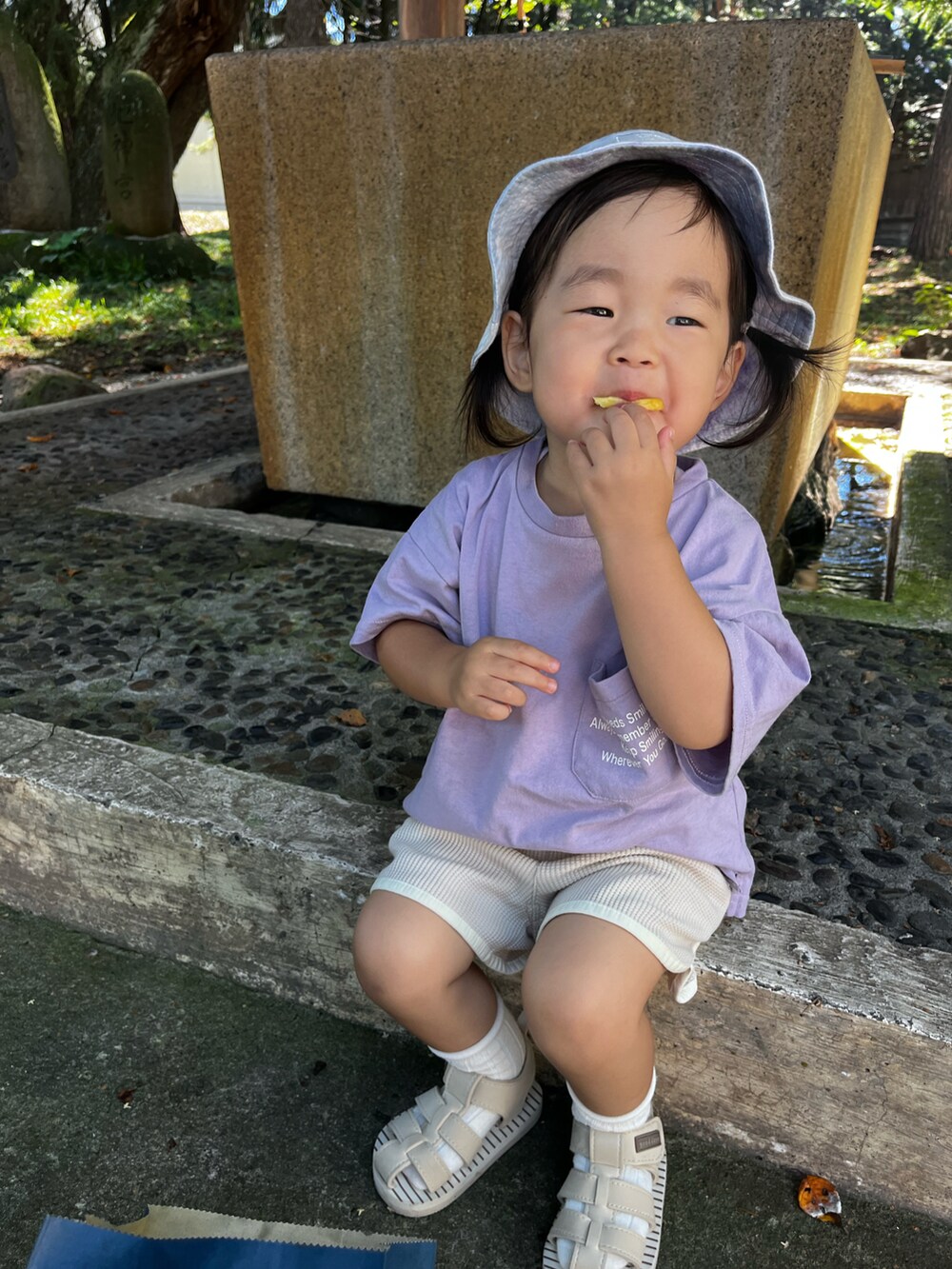 パープル系のTシャツ/カットソー、ベージュ系のパンツ、ベージュ系のサンダルを着用したキッズの夏コーディネートの4枚目の写真