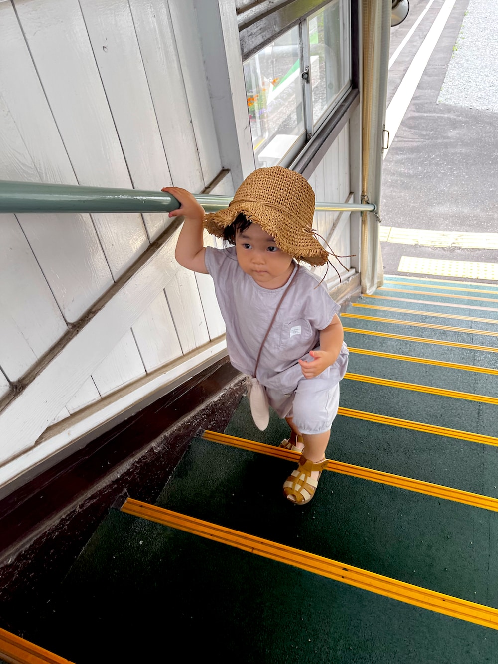 グレー系のセットアップ、ベージュ系のバッグ、ベージュ系の帽子を着用したキッズの夏コーディネートの3枚目の写真