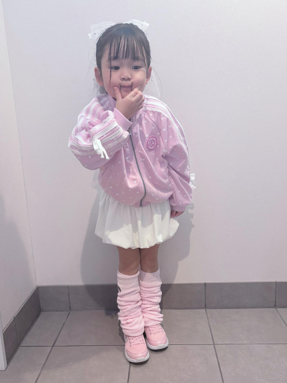 ピンク系のスニーカー、ピンク系のセットアップ、ホワイト系のスカートを着用したキッズの春コーディネートの3枚目の写真