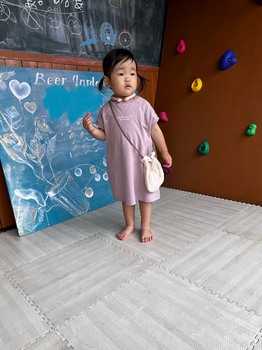 パープル系のワンピース、ベージュ系のバッグ、ベージュ系の帽子を着用したキッズの夏コーディネートの3枚目の写真
