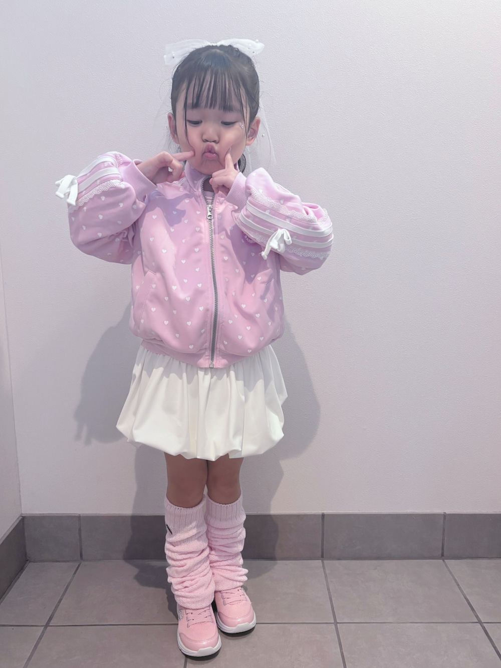 ピンク系のスニーカー、ピンク系のセットアップ、ホワイト系のスカートを着用したキッズの春コーディネートの2枚目の写真