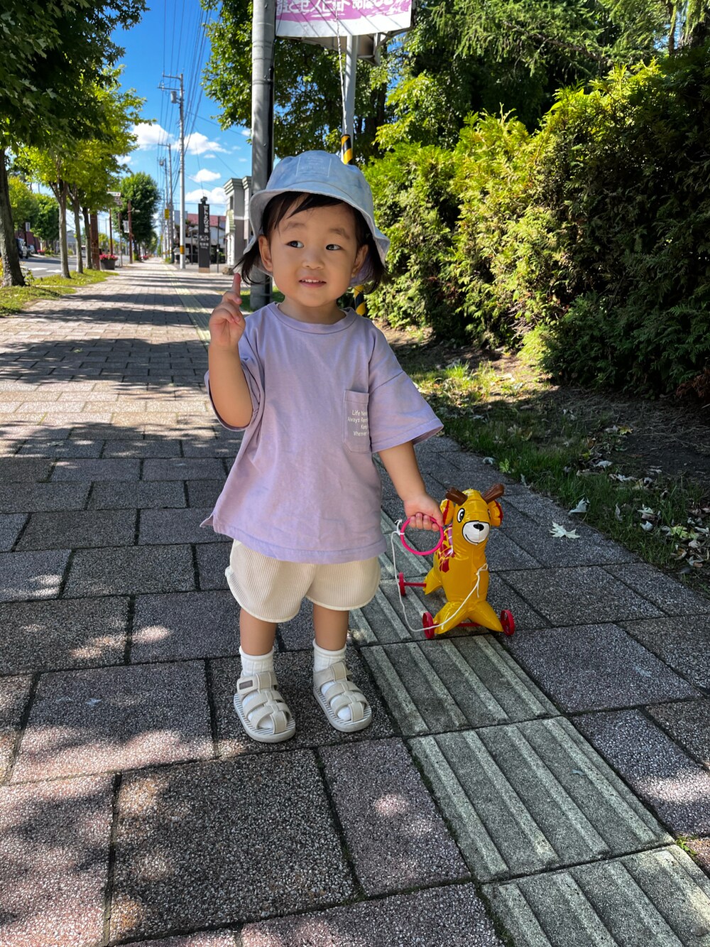 パープル系のTシャツ/カットソー、ベージュ系のパンツ、ベージュ系のサンダルを着用したキッズの夏コーディネートの5枚目の写真