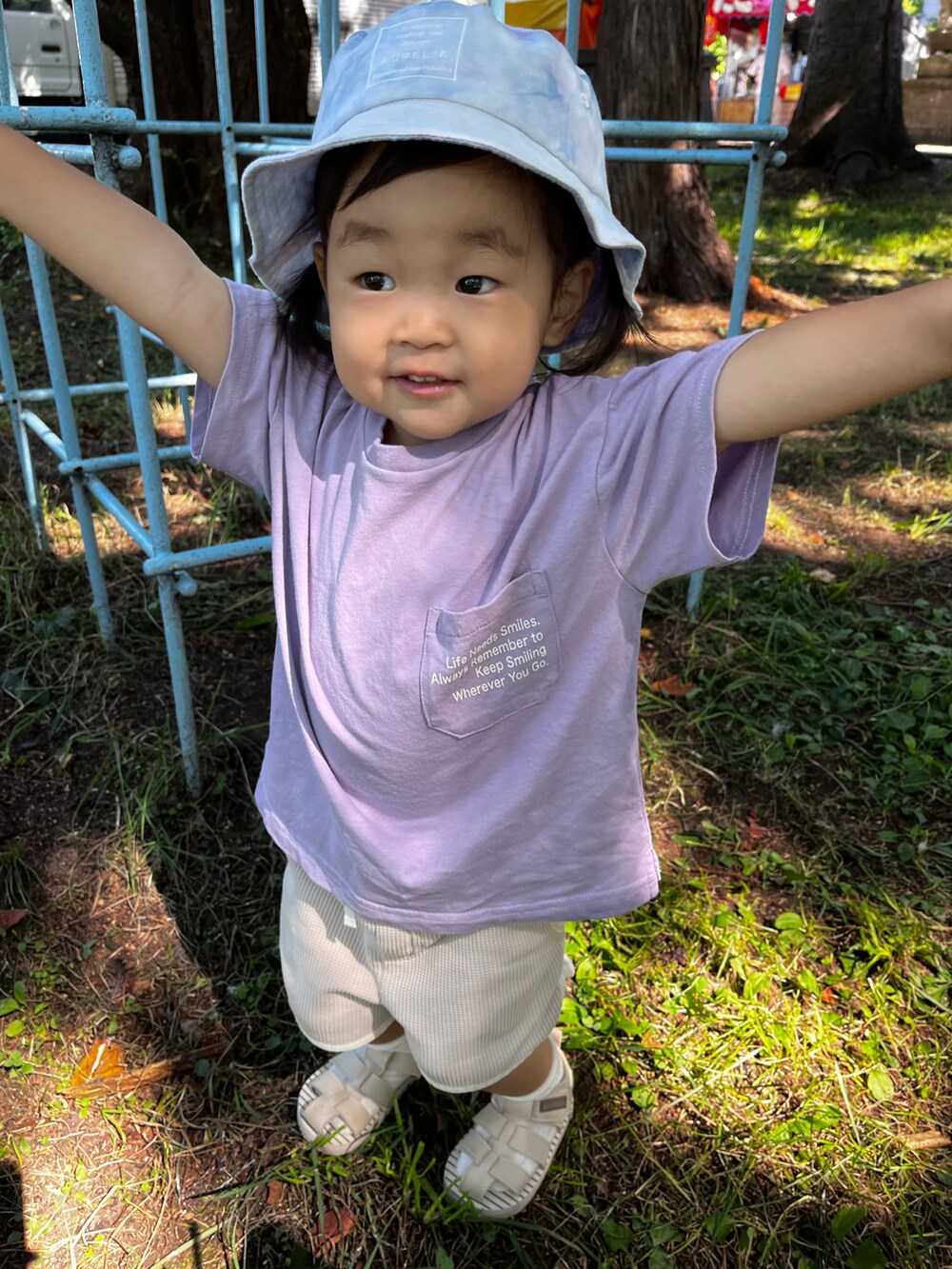 パープル系のTシャツ/カットソー、ベージュ系のパンツ、ベージュ系のサンダルを着用したキッズの夏コーディネートの3枚目の写真