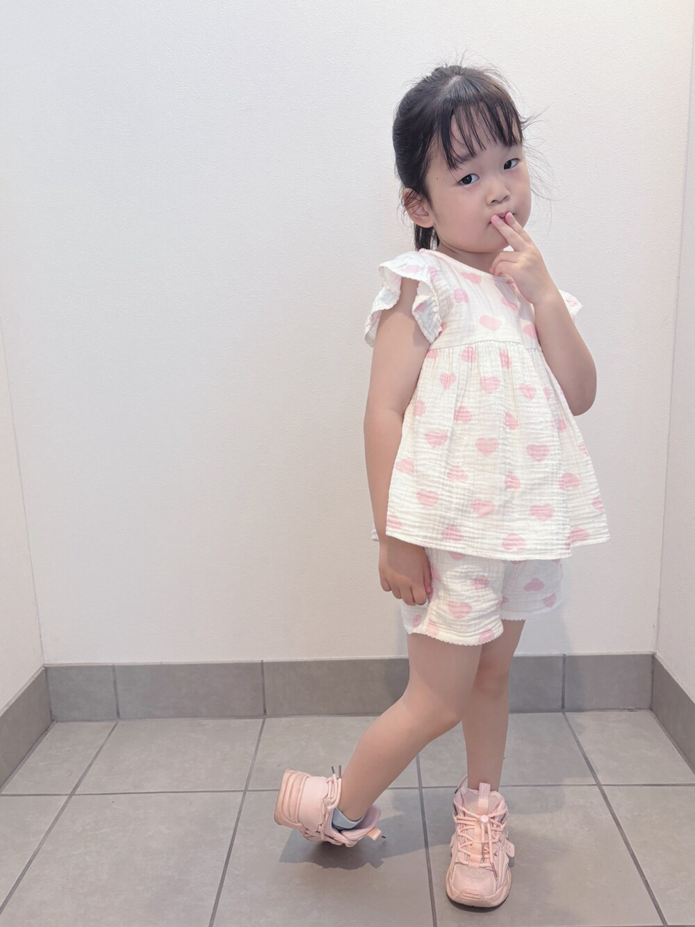 ホワイト系のトップス、ホワイト系のパンツ、ピンク系のスニーカーを着用したキッズの夏コーディネートの3枚目の写真