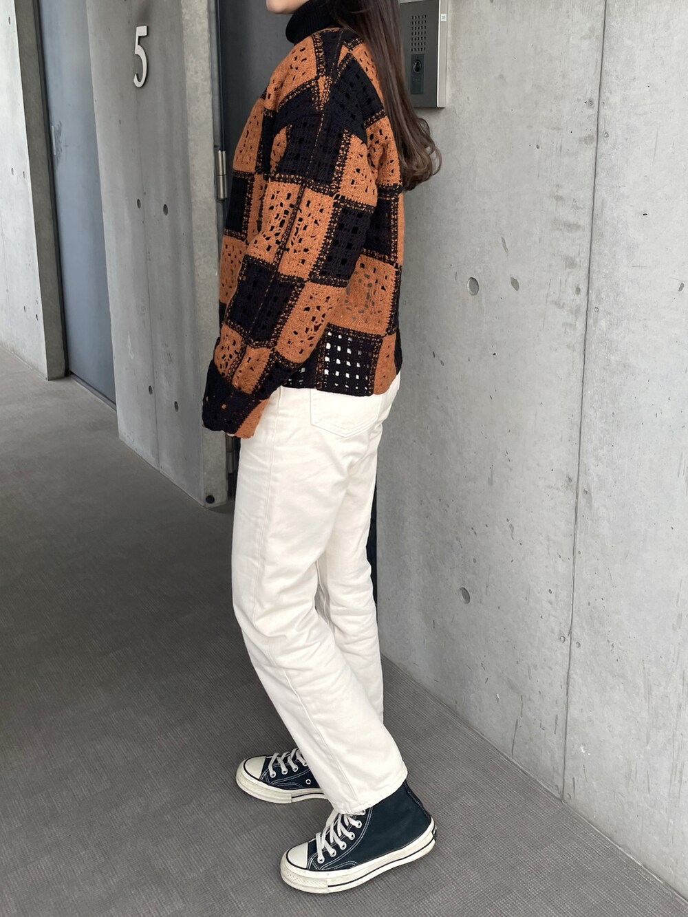 ブラック系のスニーカー、ホワイト系のデニムパンツ、ブラック系のニット/セーターを着用したレディースの冬コーディネートの3枚目の写真