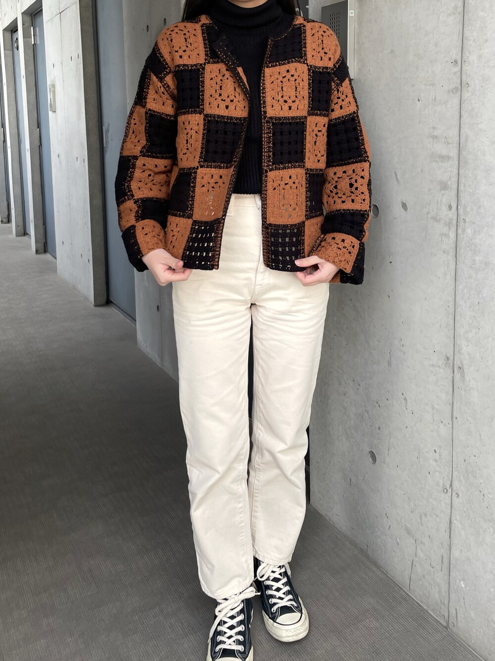 ブラック系のスニーカー、ホワイト系のデニムパンツ、ブラック系のニット/セーターを着用したレディースの冬コーディネートの2枚目の写真