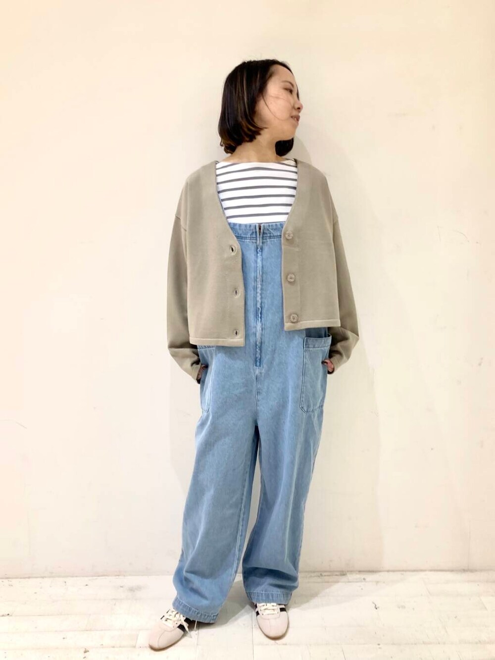 ベージュ系のカーディガン/ボレロ、グレー系のTシャツ/カットソー、ブルー系のサロペット/オーバーオールを着用したレディースの冬コーディネートの2枚目の写真