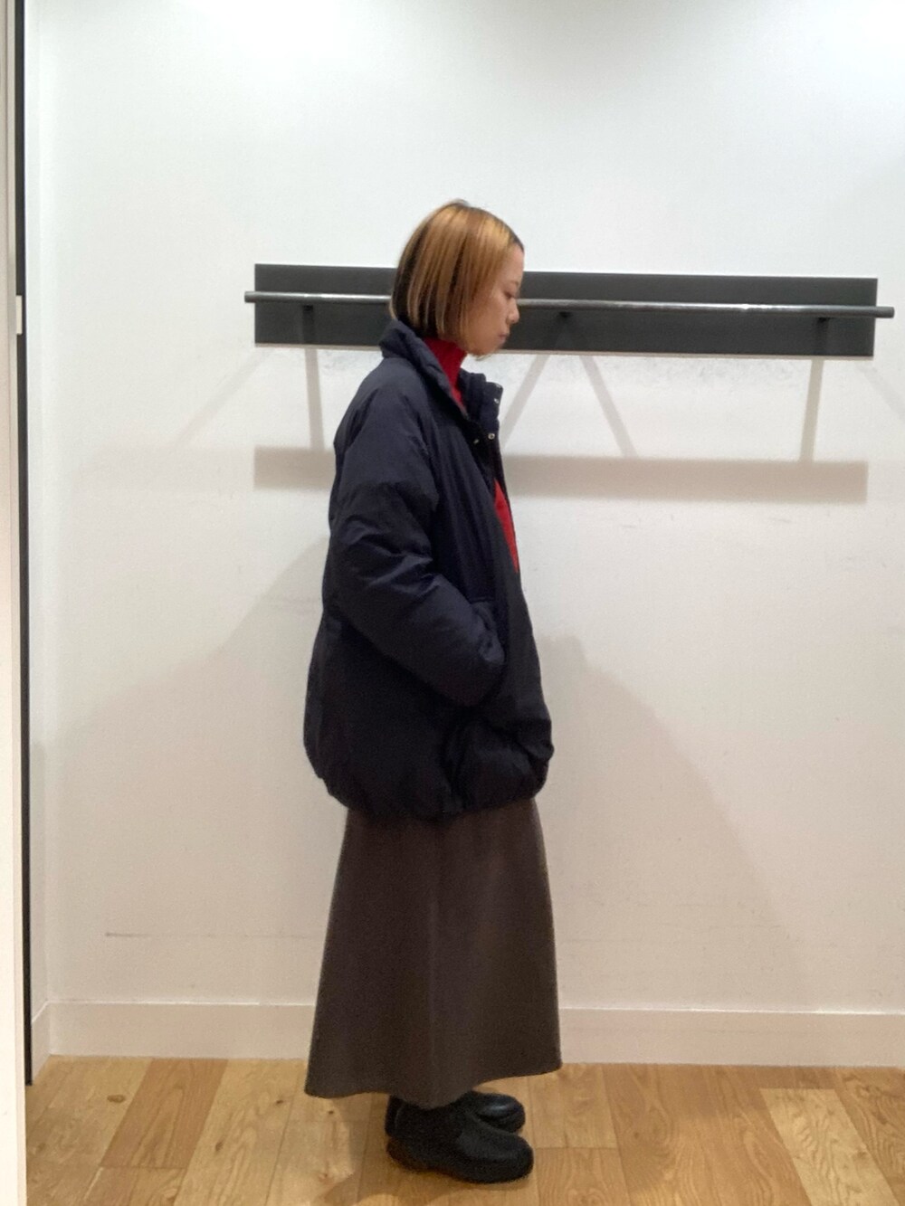 ブラック系のブルゾン、レッド系のニット/セーター、ブラウン系のスカートを着用したレディースの冬コーディネートの3枚目の写真