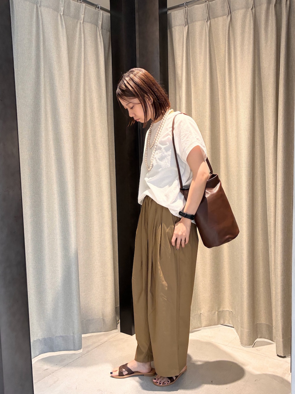 ブラウン系のサンダル、ブラウン系のショルダーバッグ、ホワイト系のTシャツ/カットソーを着用したレディースの夏コーディネートの3枚目の写真