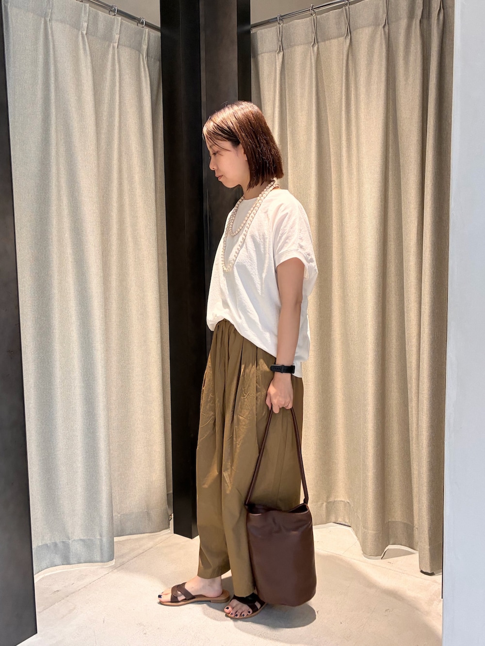 ブラウン系のサンダル、ブラウン系のショルダーバッグ、ホワイト系のTシャツ/カットソーを着用したレディースの夏コーディネートの4枚目の写真