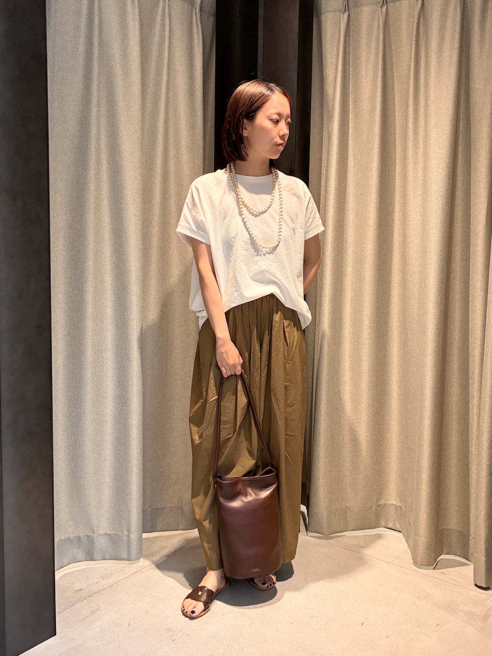 ブラウン系のサンダル、ブラウン系のショルダーバッグ、ホワイト系のTシャツ/カットソーを着用したレディースの夏コーディネートの2枚目の写真