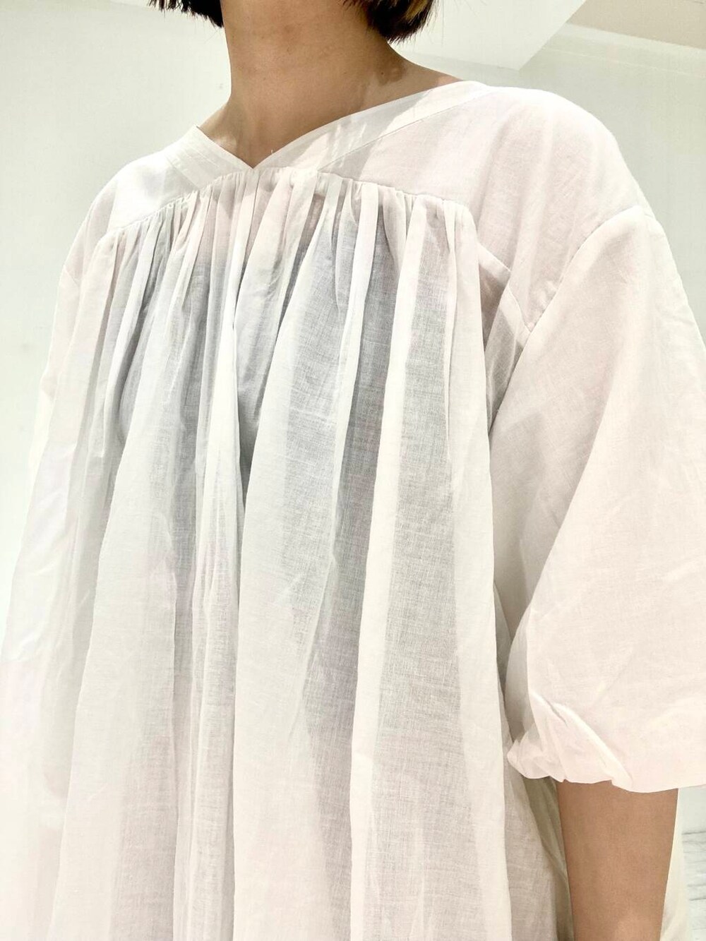 ベージュ系のその他パンツ、オレンジ系のトートバッグ、ホワイト系のチュニックを着用したレディースの夏コーディネートの3枚目の写真