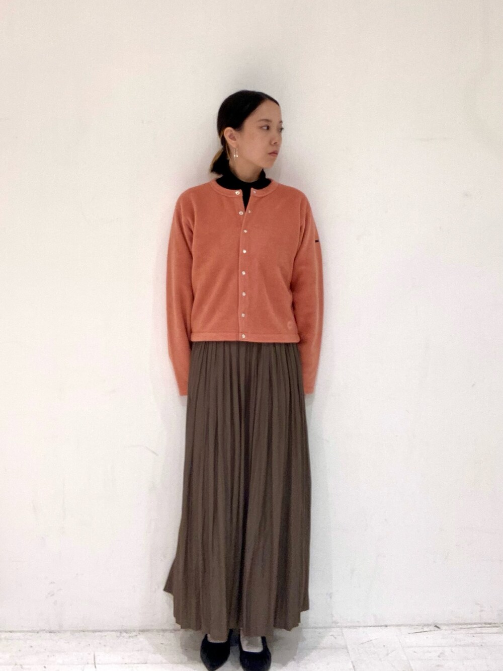 ピンク系のカーディガン/ボレロ、ブラック系のTシャツ/カットソー、ベージュ系のスカートを着用したレディースの秋コーディネートの3枚目の写真