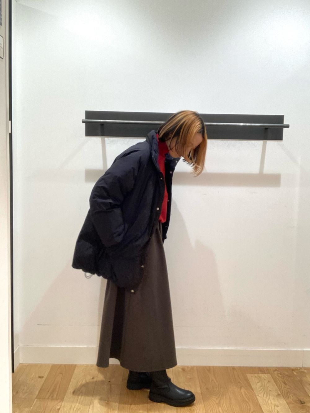 ブラック系のブルゾン、レッド系のニット/セーター、ブラウン系のスカートを着用したレディースの冬コーディネートの2枚目の写真