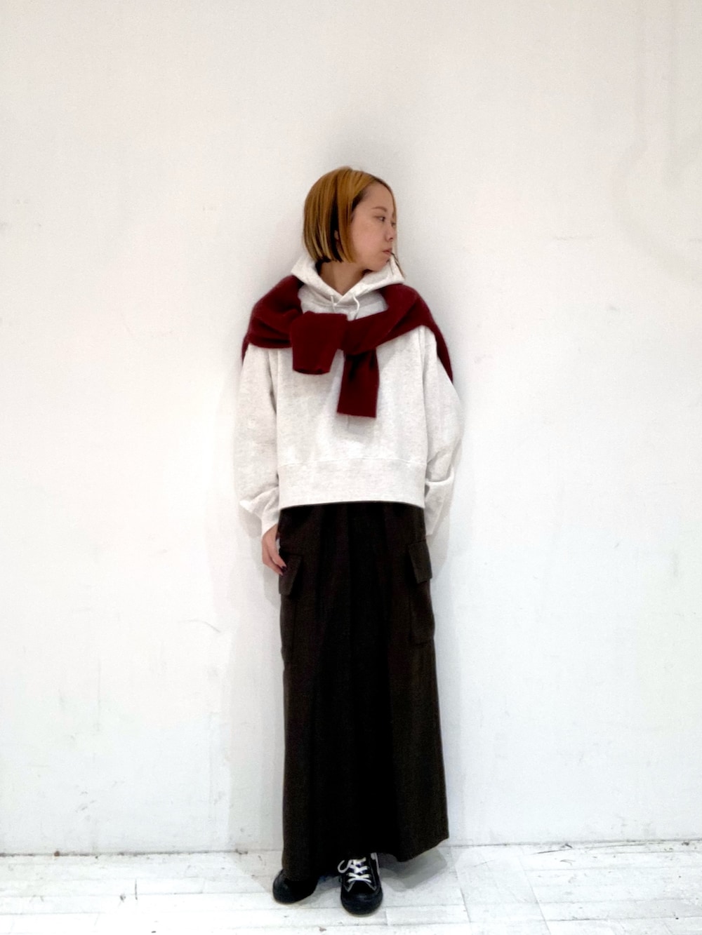 ブラウン系のスカート、ベージュ系のパーカー、レッド系のニット/セーターを着用したレディースの秋コーディネートの3枚目の写真