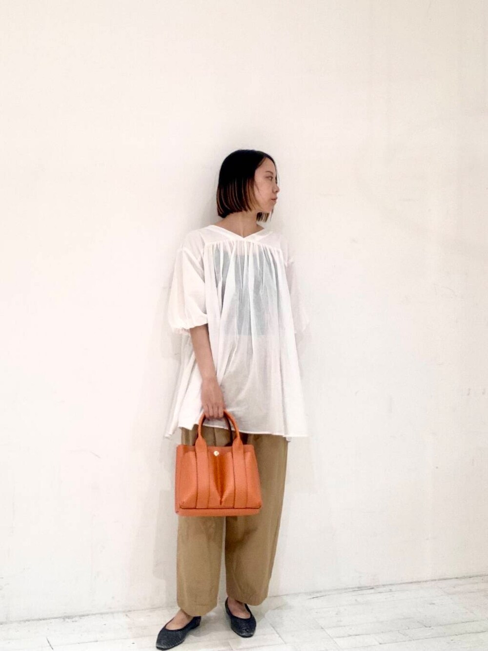 ベージュ系のその他パンツ、オレンジ系のトートバッグ、ホワイト系のチュニックを着用したレディースの夏コーディネートの2枚目の写真