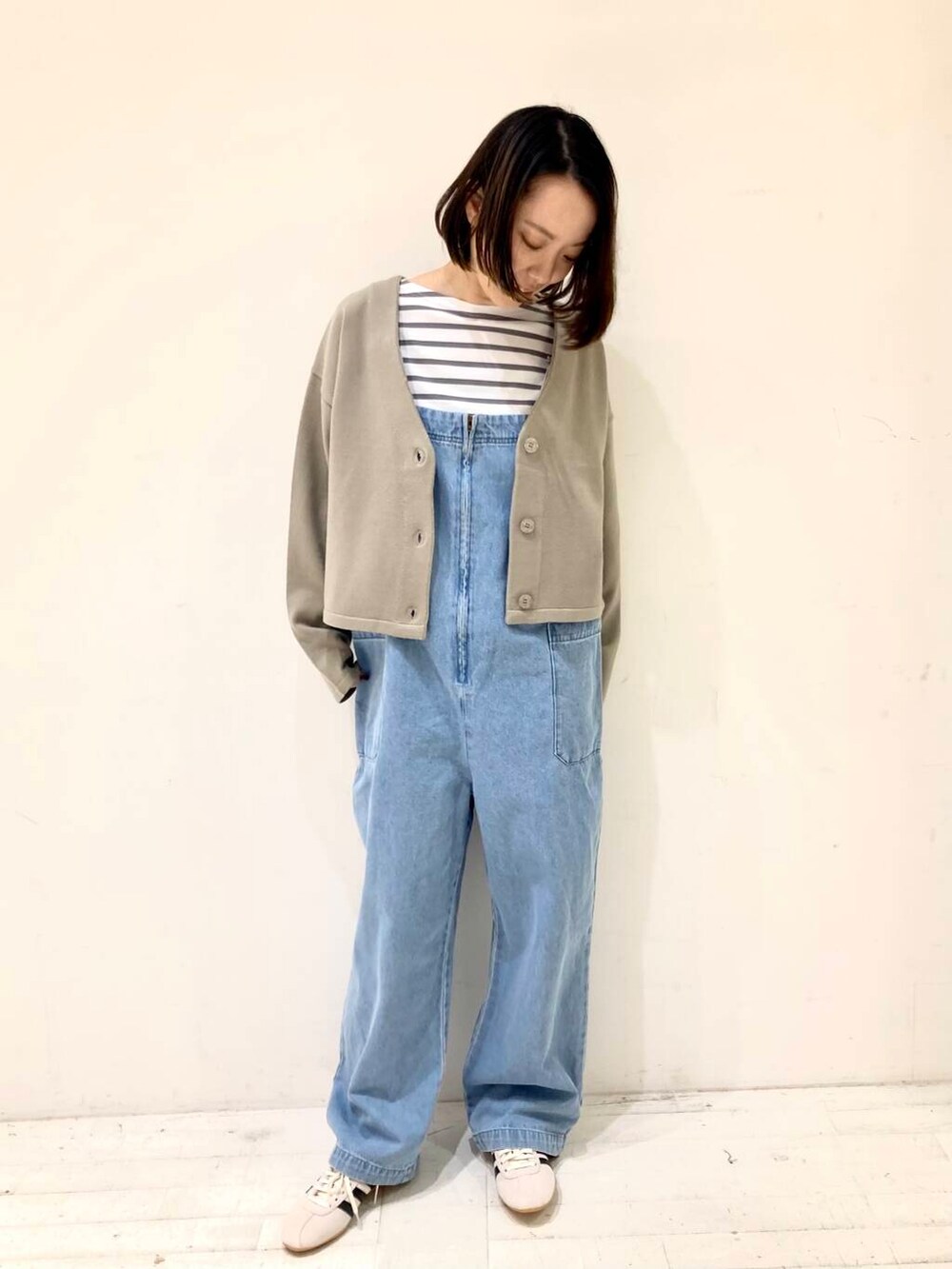 ベージュ系のカーディガン/ボレロ、グレー系のTシャツ/カットソー、ブルー系のサロペット/オーバーオールを着用したレディースの冬コーディネートの3枚目の写真