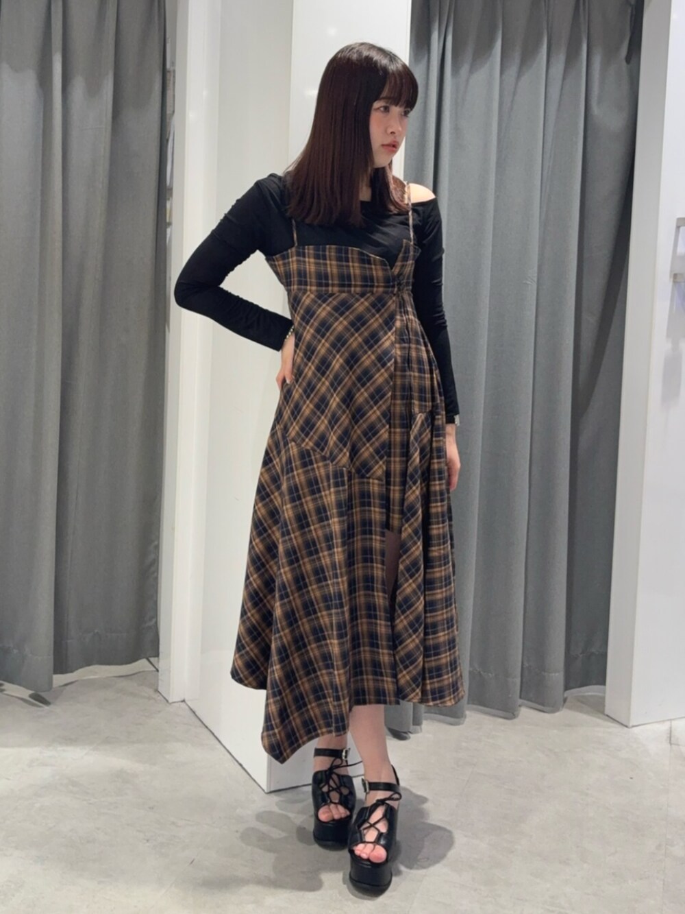 オレンジ系のワンピース、ブラック系のTシャツ/カットソー、ブラック系のサンダルを着用したレディースの春コーディネートの2枚目の写真