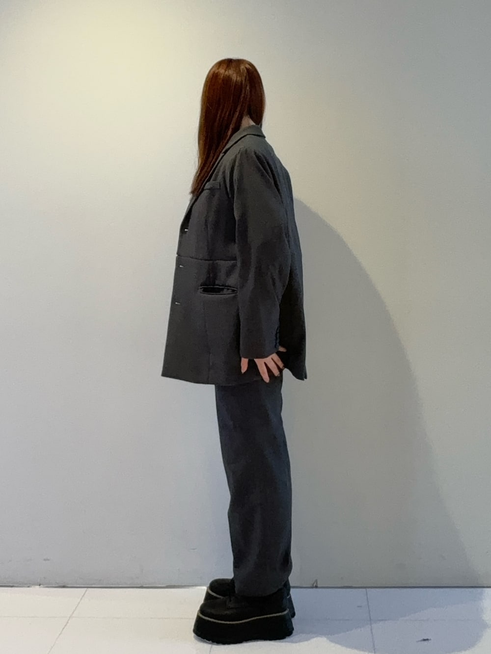 グレー系のテーラードジャケット、グレー系のスラックス、レッド系のTシャツ/カットソーを着用したレディースの秋コーディネートの2枚目の写真