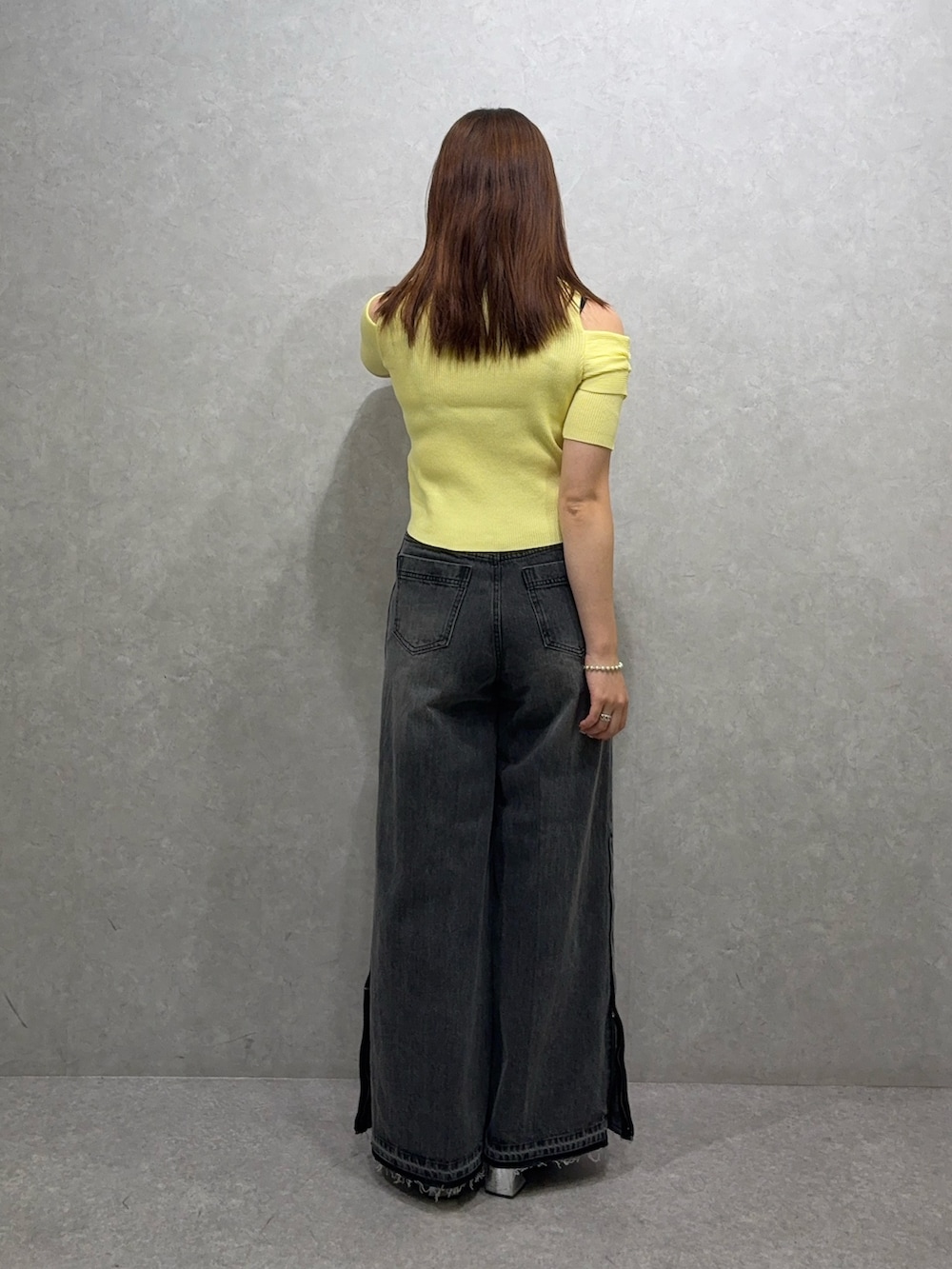 イエロー系のニット/セーター、ブラック系のデニムパンツ、ブラック系のパンプスを着用したレディースの夏コーディネートの3枚目の写真
