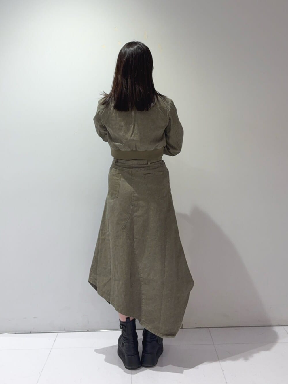 ブラック系のブーツ、グリーン系のブルゾン、グリーン系のスカートを着用したレディースの春コーディネートの3枚目の写真