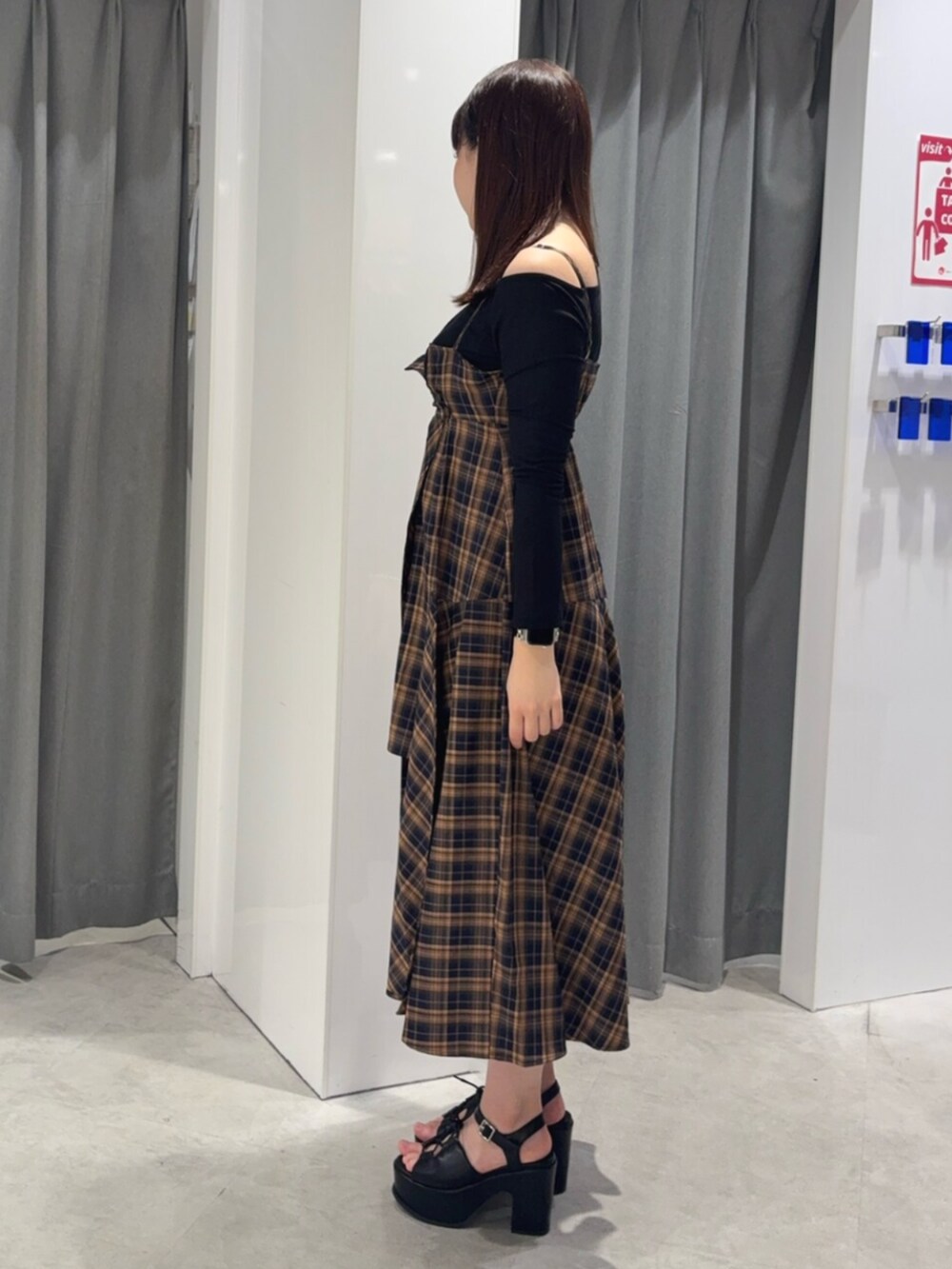 オレンジ系のワンピース、ブラック系のTシャツ/カットソー、ブラック系のサンダルを着用したレディースの春コーディネートの3枚目の写真