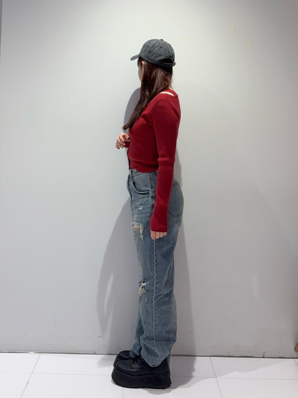 レッド系のニット/セーター、ブルー系のデニムパンツ、ブラック系のブーツを着用したレディースの冬コーディネートの2枚目の写真