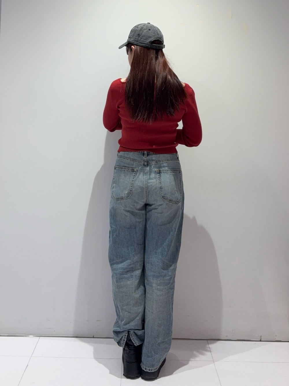 レッド系のニット/セーター、ブルー系のデニムパンツ、ブラック系のブーツを着用したレディースの冬コーディネートの3枚目の写真