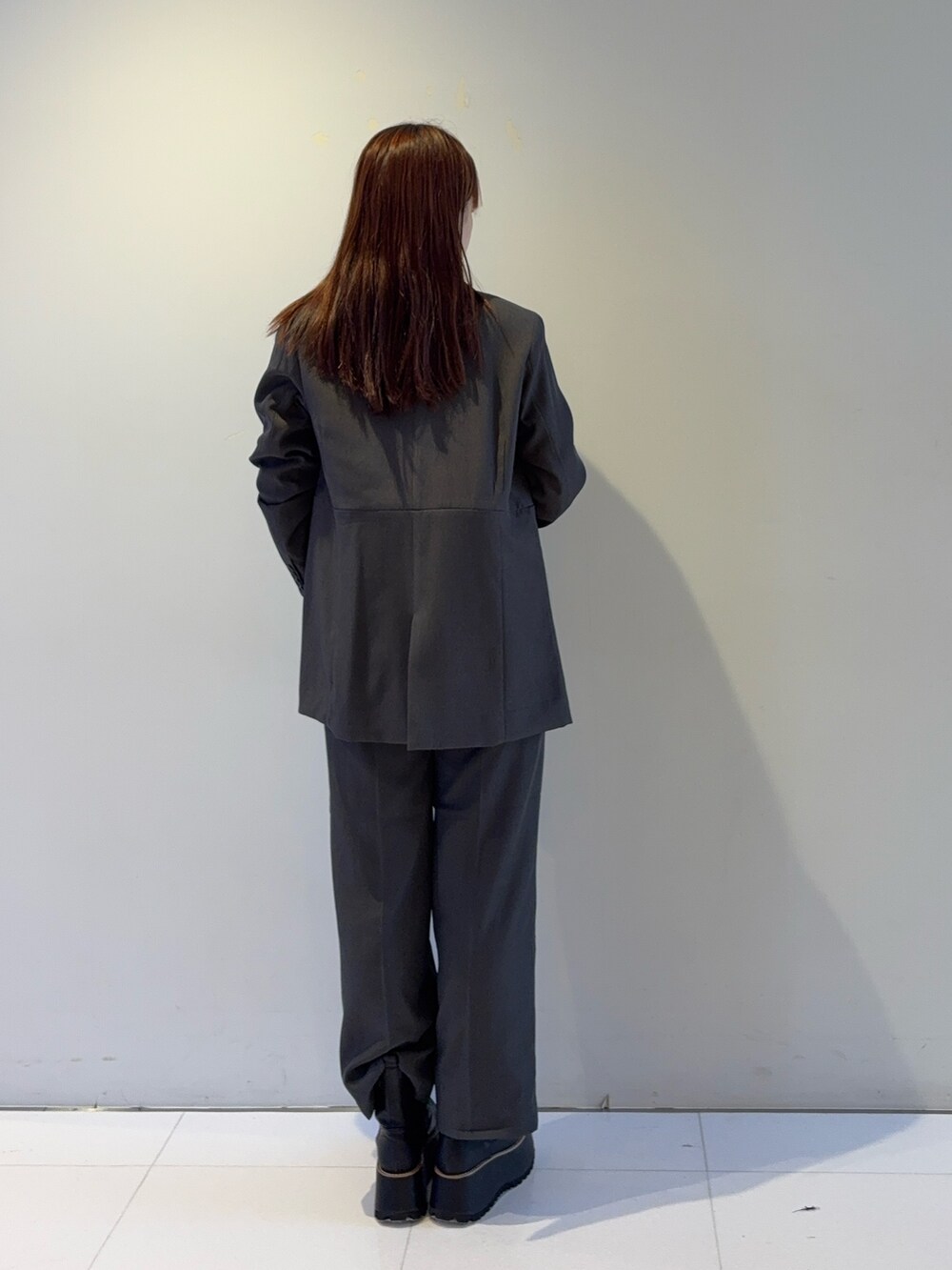 グレー系のテーラードジャケット、グレー系のスラックス、レッド系のTシャツ/カットソーを着用したレディースの秋コーディネートの3枚目の写真