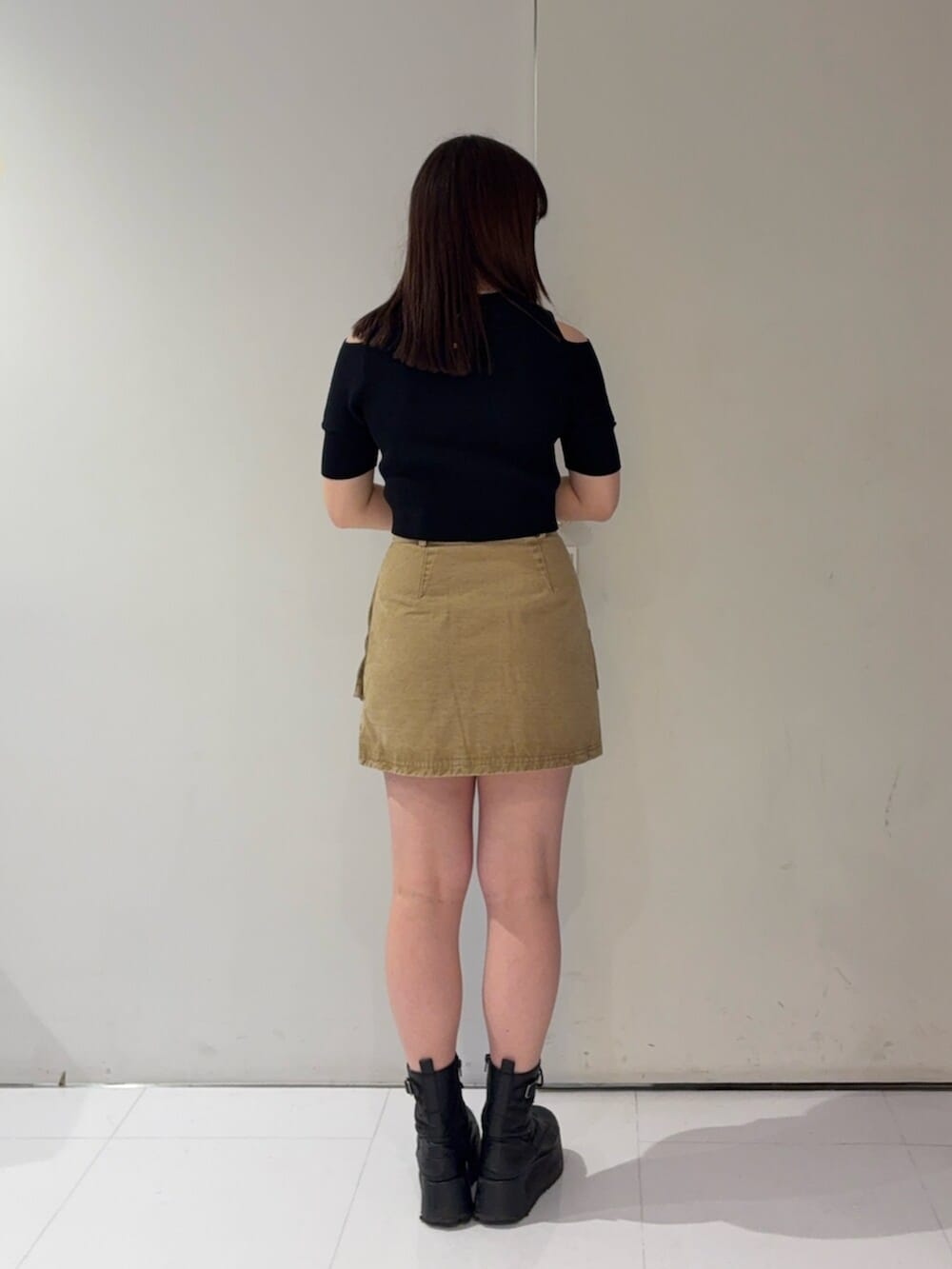 ブラック系のブーツ、ブラック系のニット/セーター、ベージュ系のスカートを着用したレディースの春コーディネートの3枚目の写真