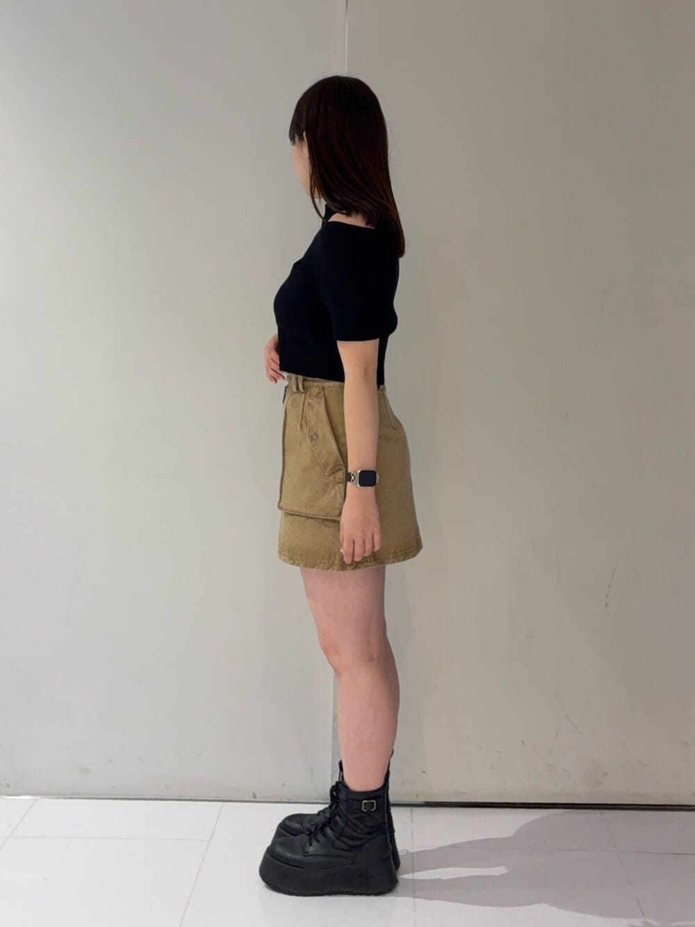 ブラック系のブーツ、ブラック系のニット/セーター、ベージュ系のスカートを着用したレディースの春コーディネートの2枚目の写真