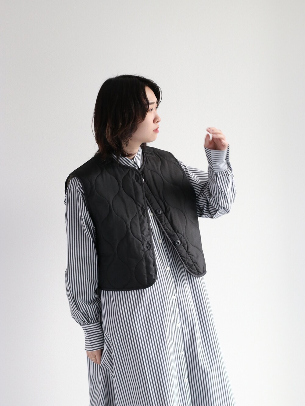 グリーン系のベスト、ホワイト系のスウェット、ホワイト系のバッグを着用したレディースの秋コーディネートの2枚目の写真