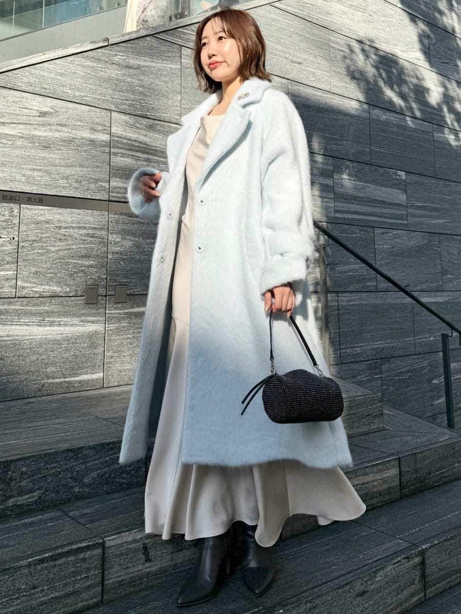 ブルー系のチェスターコート、ホワイト系のワンピースを着用したレディースの冬コーディネートの5枚目の写真