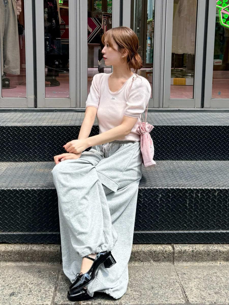 ピンク系のニット/セーター、グレー系のその他パンツ、ピンク系のハンドバッグを着用したレディースの夏コーディネートの3枚目の写真