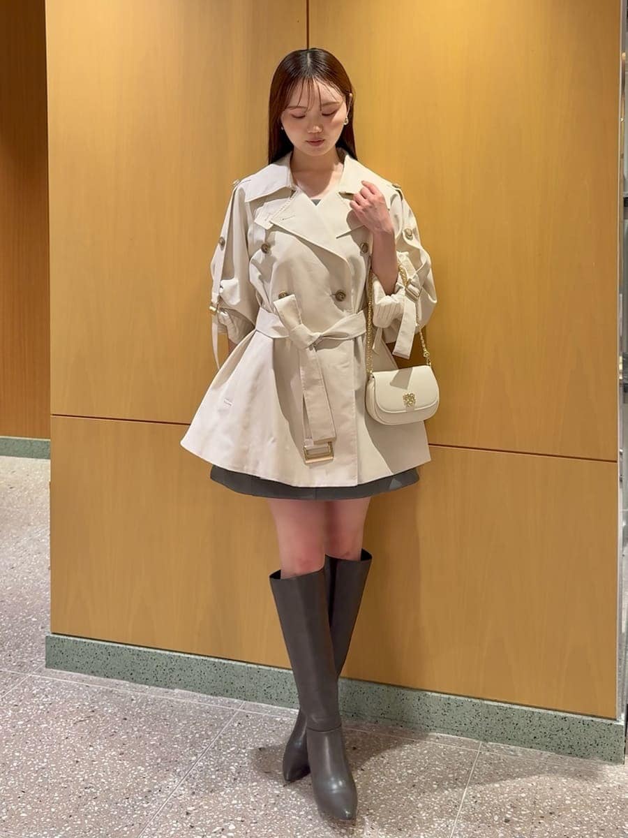 グレー系のブーツ、ホワイト系のトレンチコート、グレー系のワンピースを着用したレディースの冬コーディネートの2枚目の写真