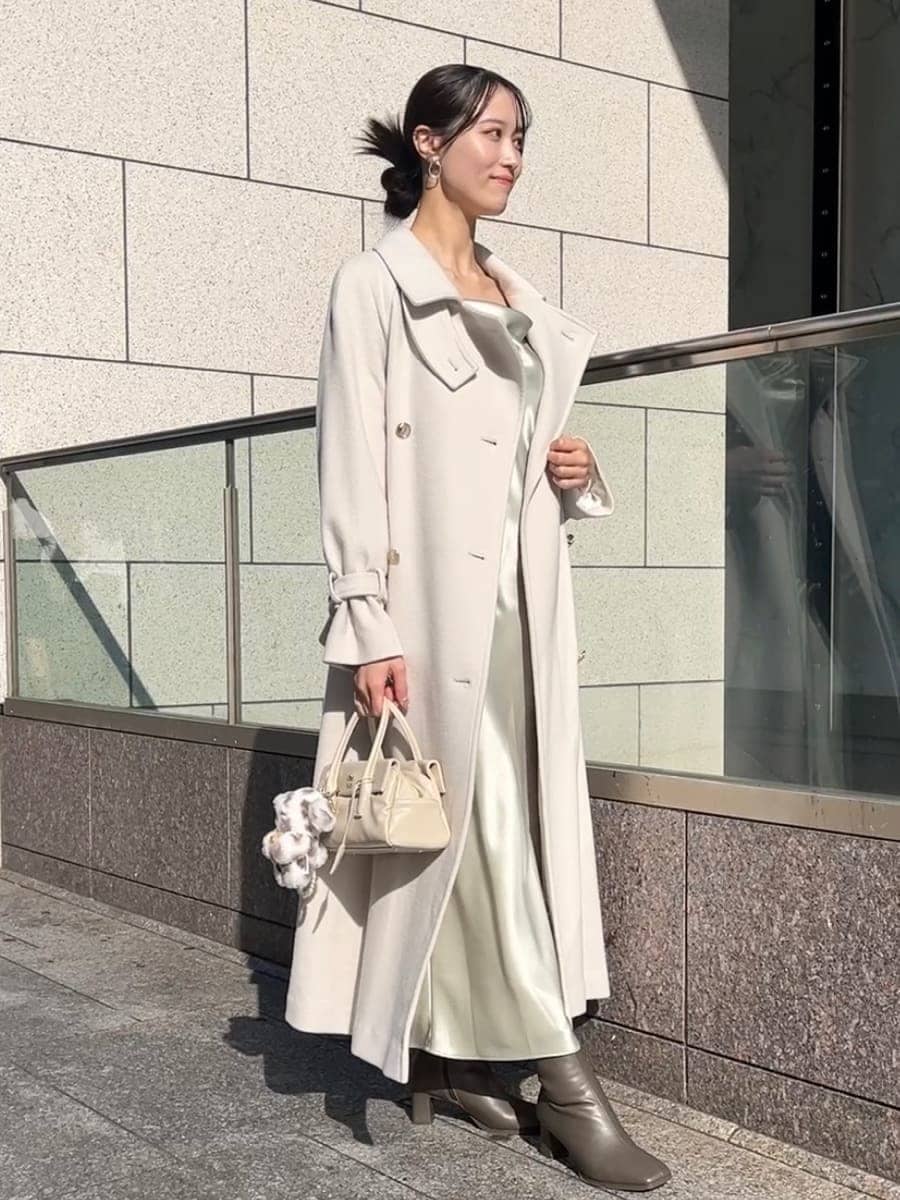 ホワイト系のチェスターコート、ホワイト系のワンピース、ホワイト系のボストンバッグを着用したレディースの秋コーディネートの2枚目の写真