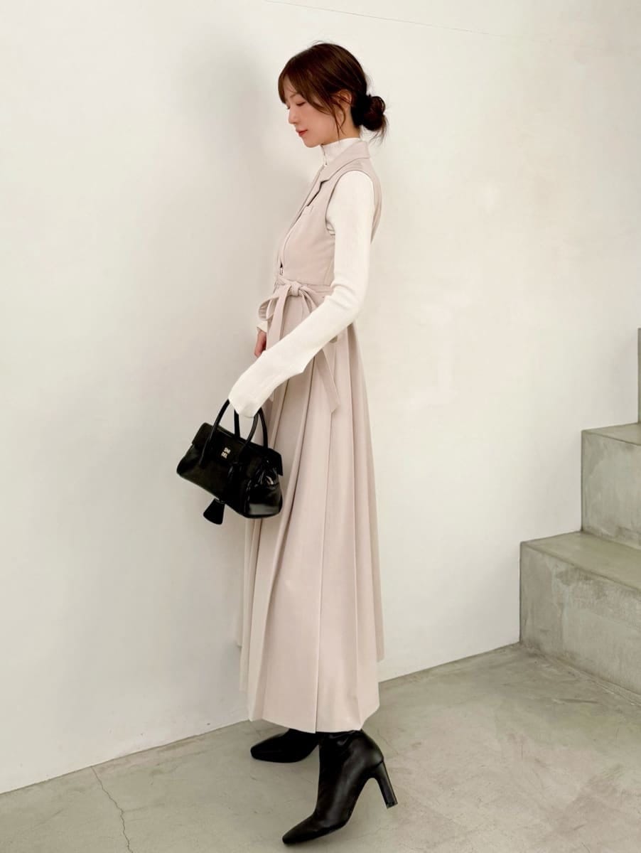 ブラック系のブーツ、ベージュ系のワンピース、ホワイト系のニット/セーターを着用したレディースの秋コーディネートの2枚目の写真