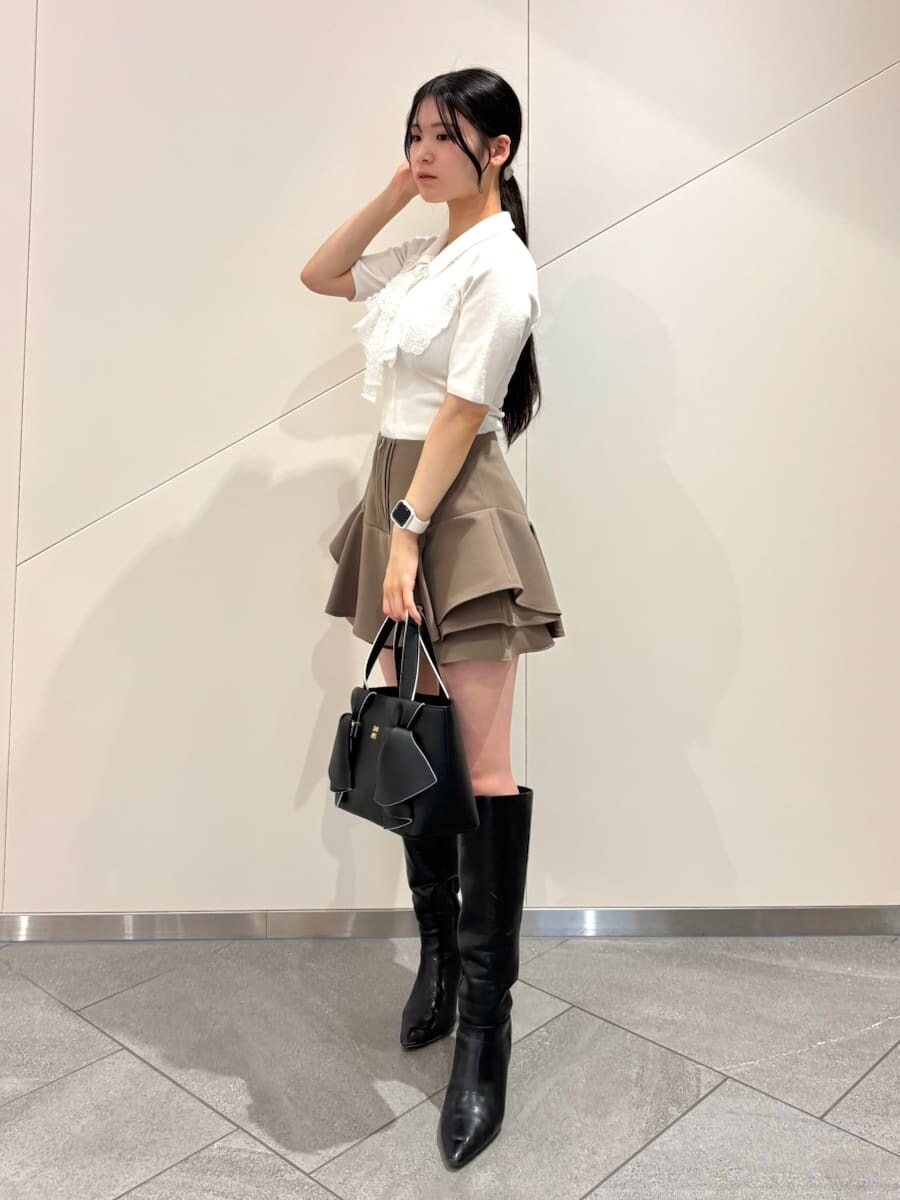 ブラック系のブーツ、ホワイト系のニット/セーター、ブラック系のハンドバッグを着用したレディースの冬コーディネートの2枚目の写真