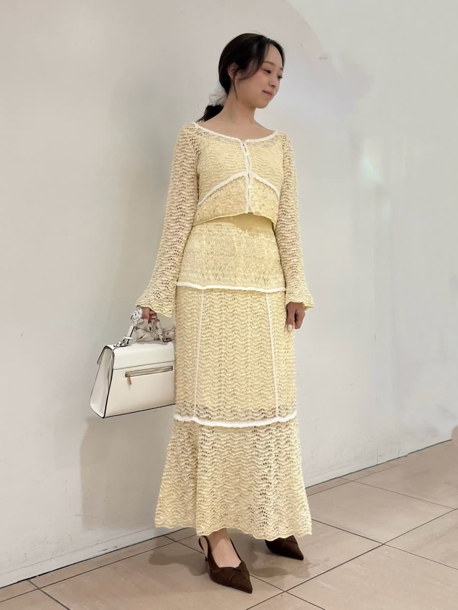 イエロー系のスカート、ブラウン系のパンプス、ホワイト系のハンドバッグを着用したレディースの冬コーディネートの2枚目の写真