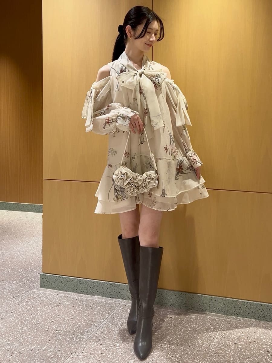 グレー系のブーツ、イエロー系のワンピース、ホワイト系のハンドバッグを着用したレディースの冬コーディネートの3枚目の写真