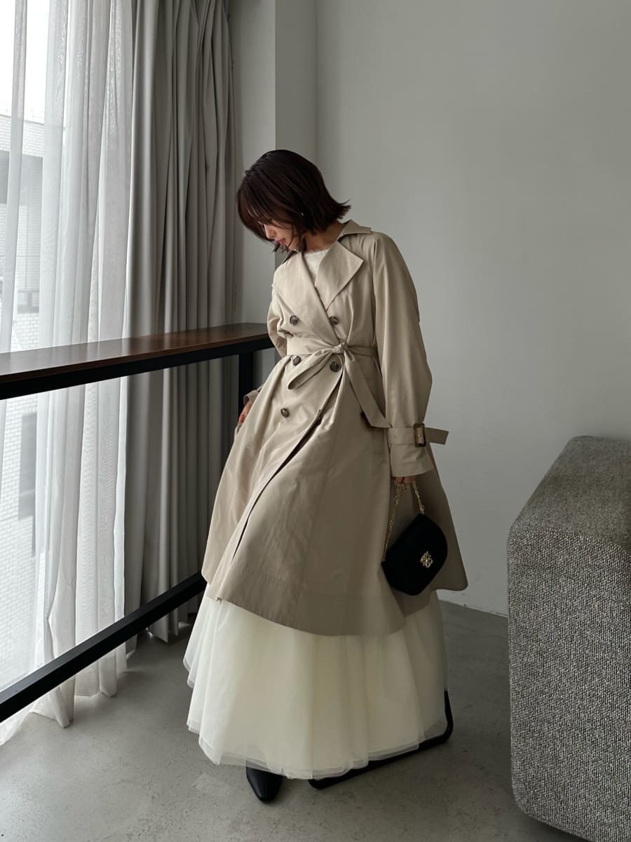 ベージュ系のトレンチコート、ベージュ系のワンピース、ブラック系のショルダーバッグを着用したレディースの春コーディネートの5枚目の写真