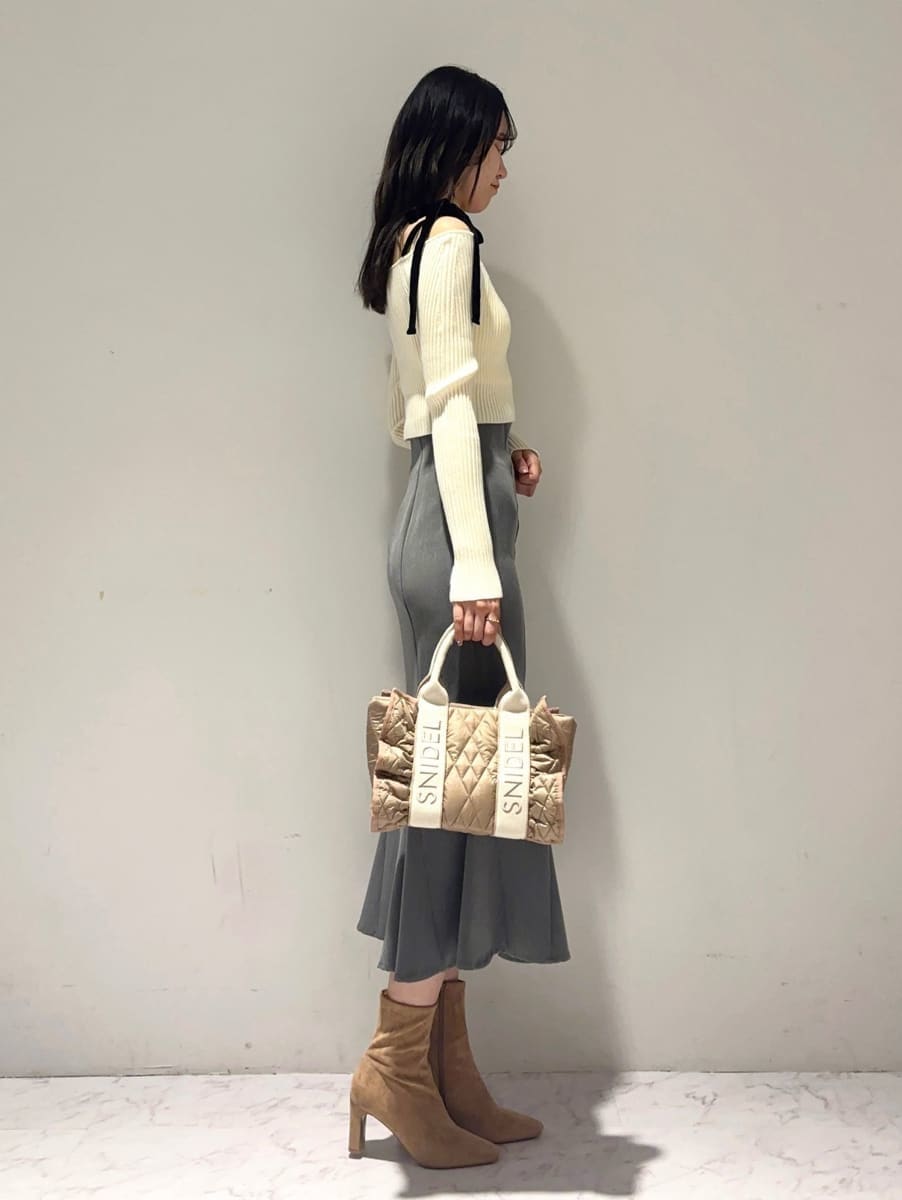 ホワイト系のニット/セーター、グレー系のスカート、ベージュ系のハンドバッグを着用したレディースの秋コーディネートの3枚目の写真