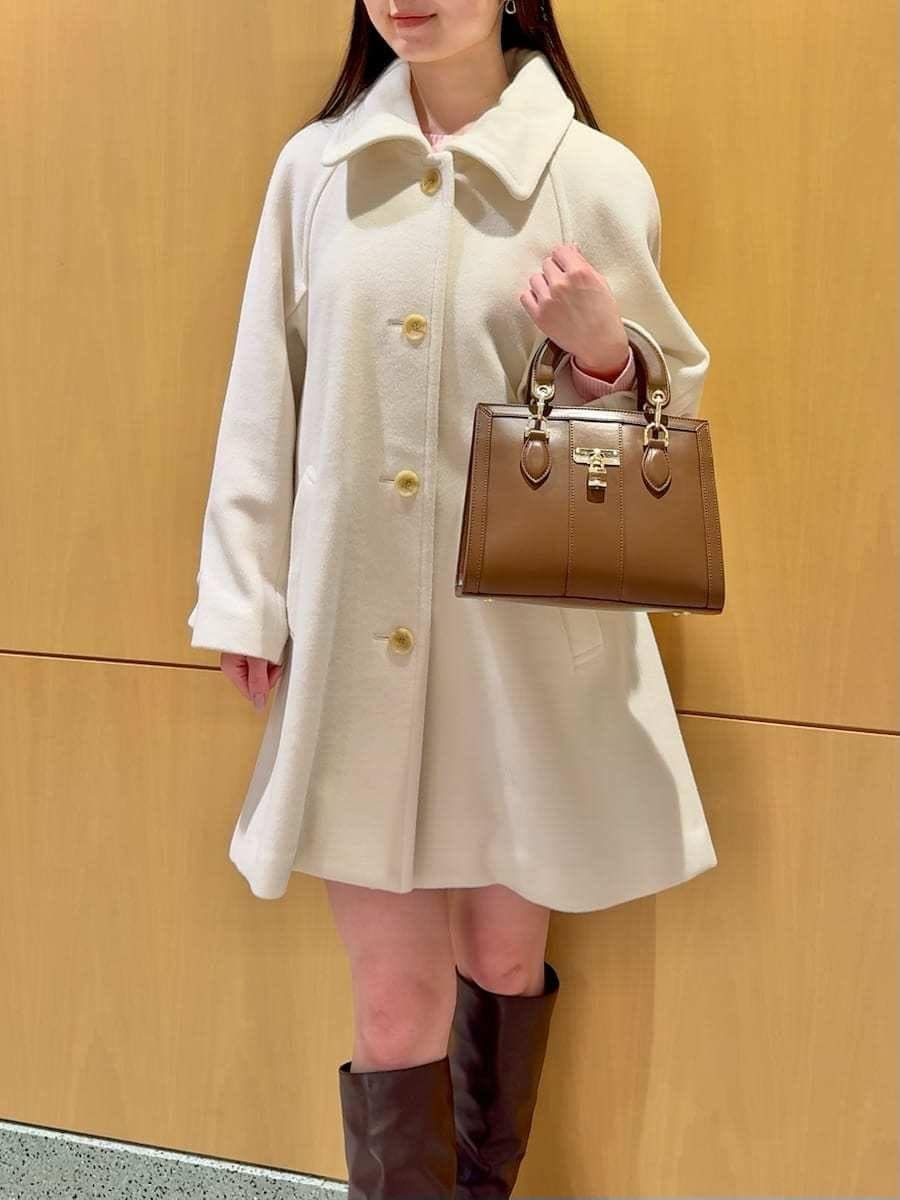 ホワイト系のステンカラーコート、その他のその他パンツ、ブラウン系のハンドバッグを着用したレディースの冬コーディネートの9枚目の写真