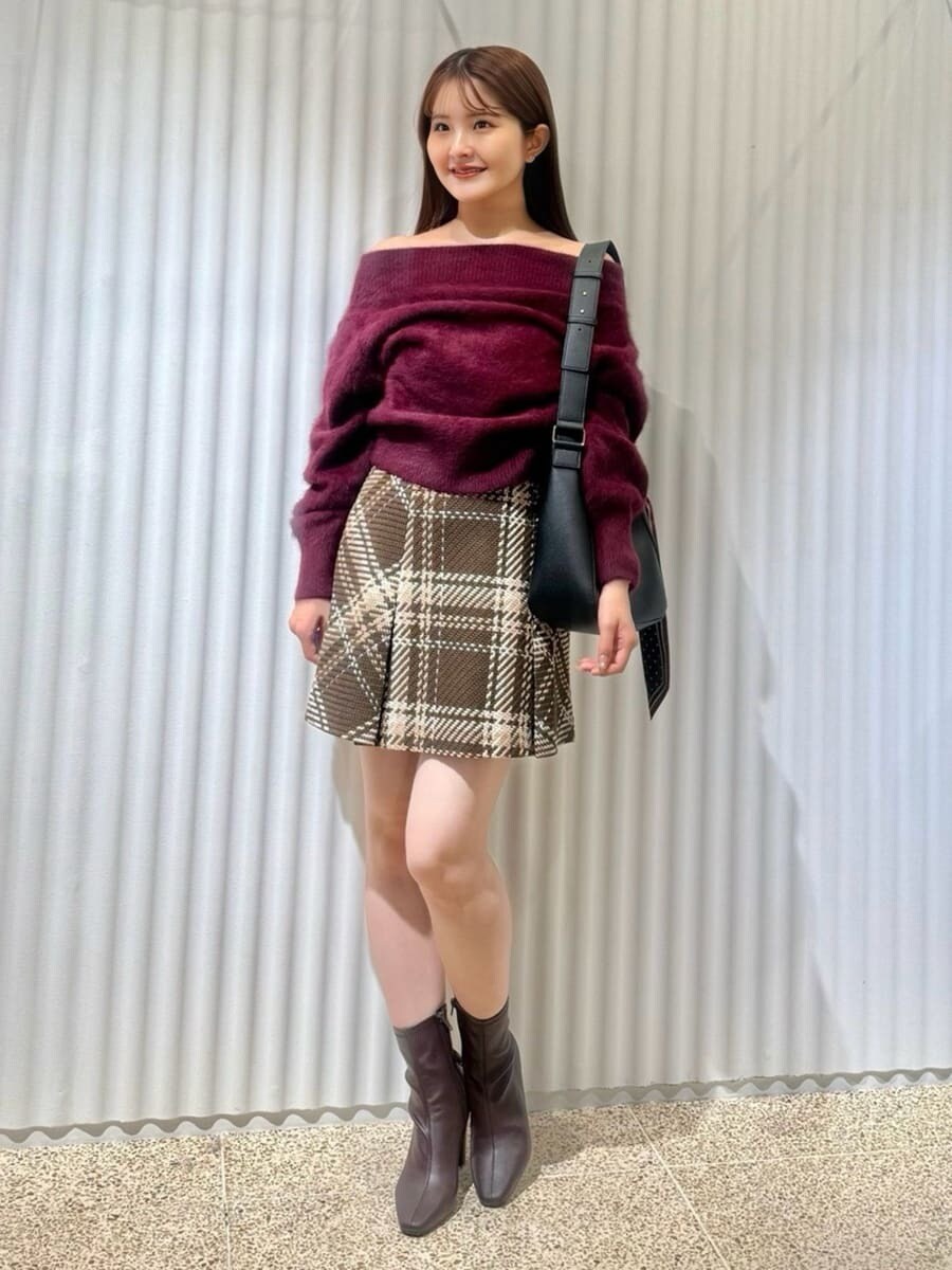 レッド系のニット/セーター、ブラウン系のスカート、レッド系のブーツを着用したレディースの秋コーディネートの2枚目の写真