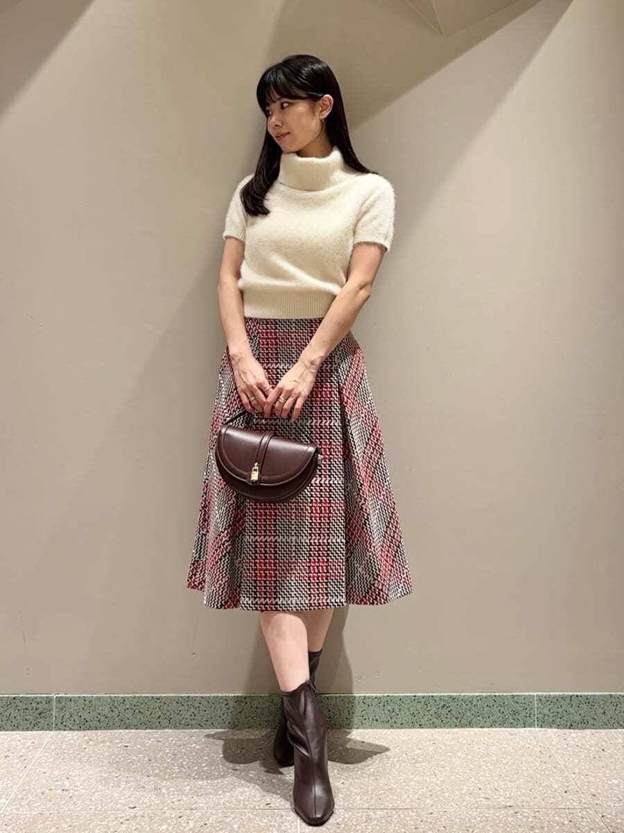 ベージュ系のニット/セーター、レッド系のスカート、ブラウン系のハンドバッグを着用したレディースの秋コーディネートの4枚目の写真