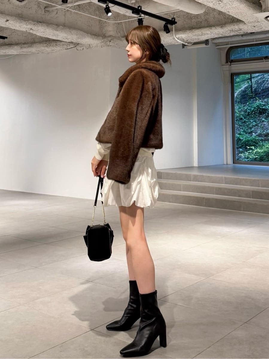 ホワイト系のキャミソール、ブラック系のブーツ、ブラウン系のステンカラーコートを着用したレディースの秋コーディネートの2枚目の写真