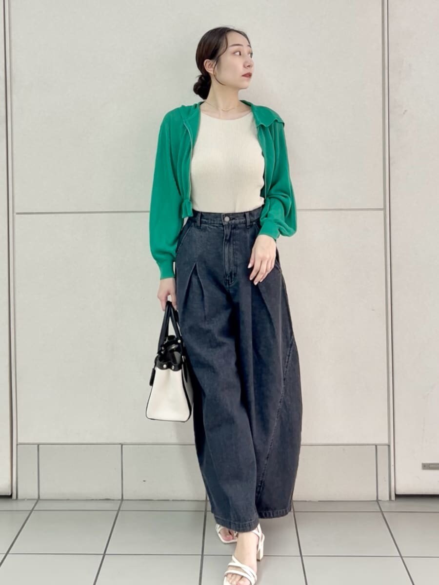ブラック系のデニムパンツ、ベージュ系のニット/セーター、ブラック系のハンドバッグを着用したレディースの夏コーディネートの2枚目の写真