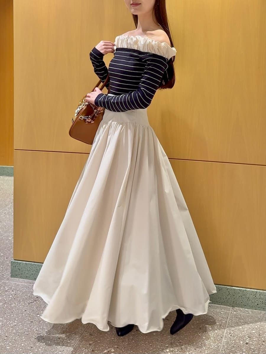 ブラック系のブーツ、ホワイト系のスカート、その他のニット/セーターを着用したレディースの冬コーディネートの2枚目の写真